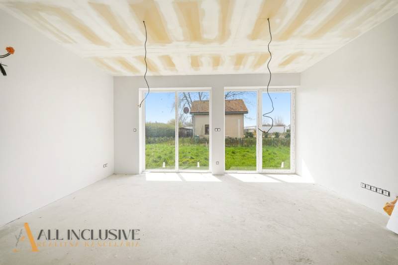 A spacious room in a cottage with large windows and a view of the garden.