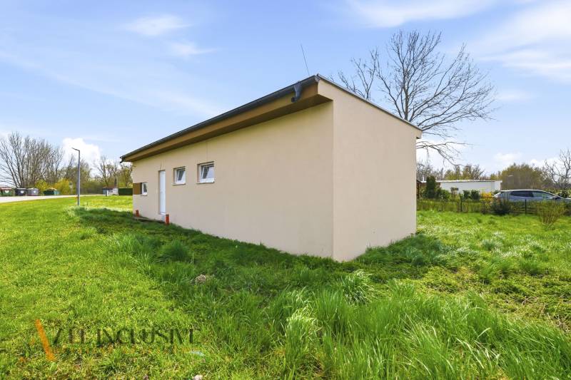 A cottage in Vojka nad Dunajom surrounded by greenery, next to an asphalt road.