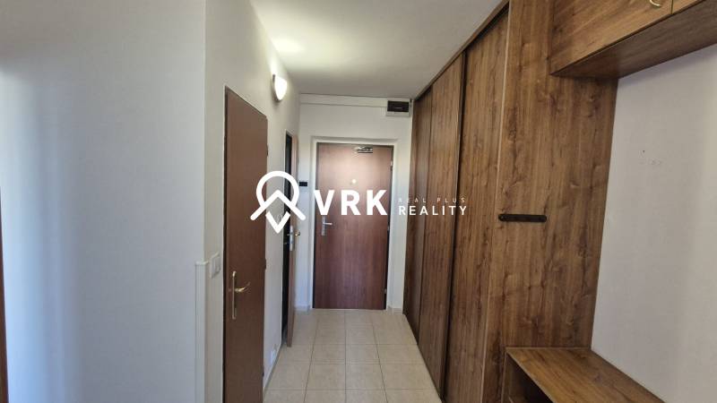 A hallway with tiled flooring and cabinets with a wooden decor in a 2-room apartment.