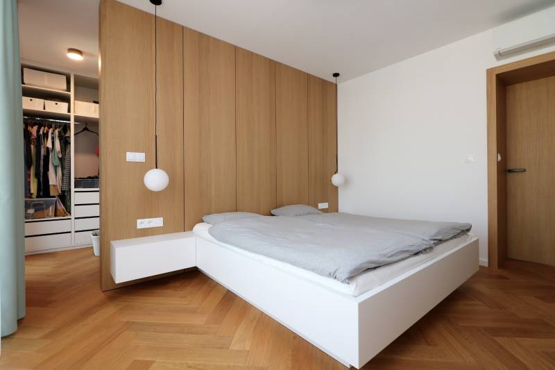 Bedroom in a 4-room apartment with a bed, wooden decor flooring, and a wardrobe.