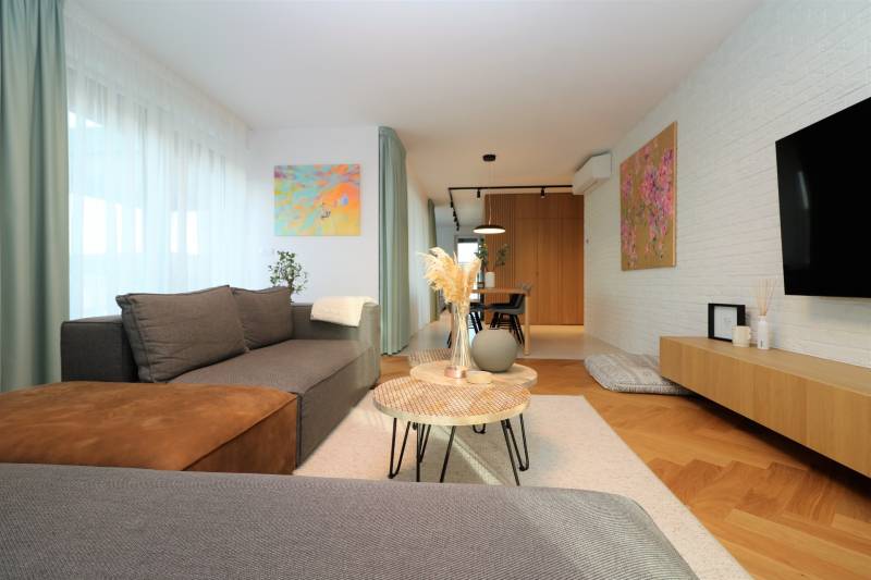A stylish living room in a 4-room apartment with a wood-patterned floor and artistic paintings.