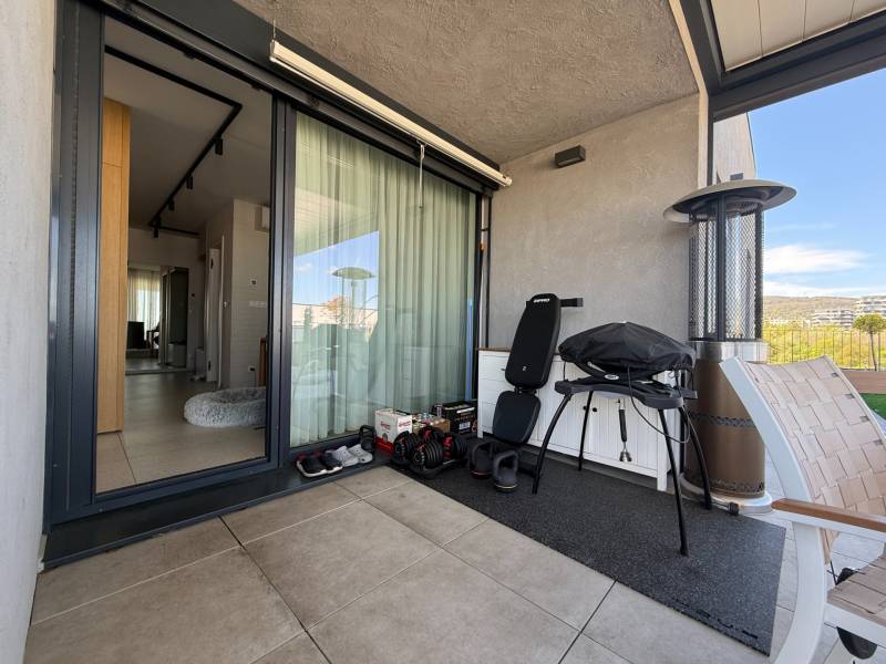 Balcony of a 4-room apartment with a grill, chair, and view of Dúbravka.