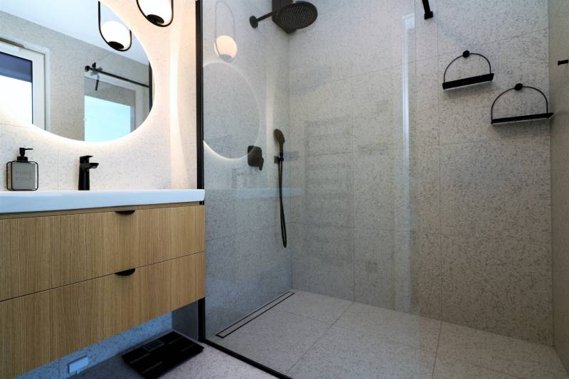 Shower enclosure with glass doors and a sink in a 4-room apartment.