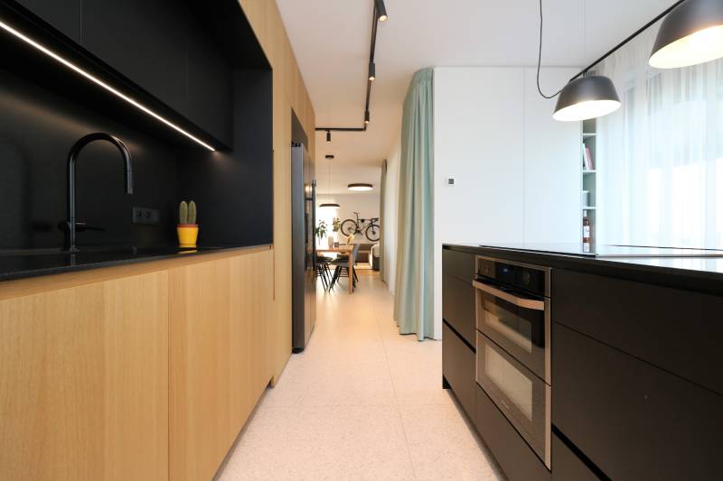 A kitchen in a 4-room apartment with wooden decor and black accessories.