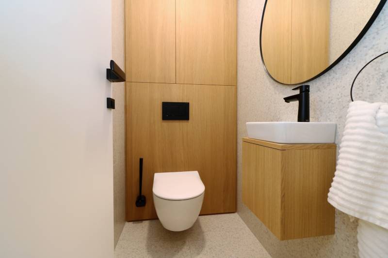 A toilet with a wooden decor floor and a modern sink in a 4-room apartment.