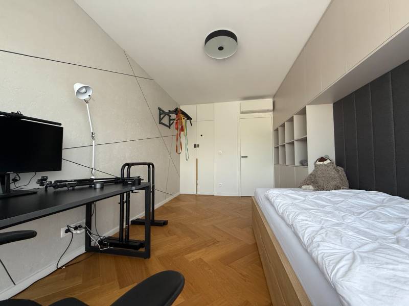 A room in a 4-room apartment with a bed, a table, and a floor with a wooden decor.