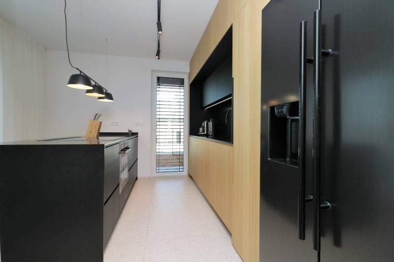 A kitchen in a 4-room apartment with a black countertop and wooden cabinets.