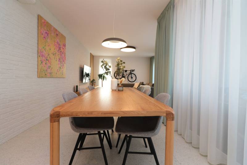 Dining room with a large wooden table, chairs, and curtains in a 4-room apartment.