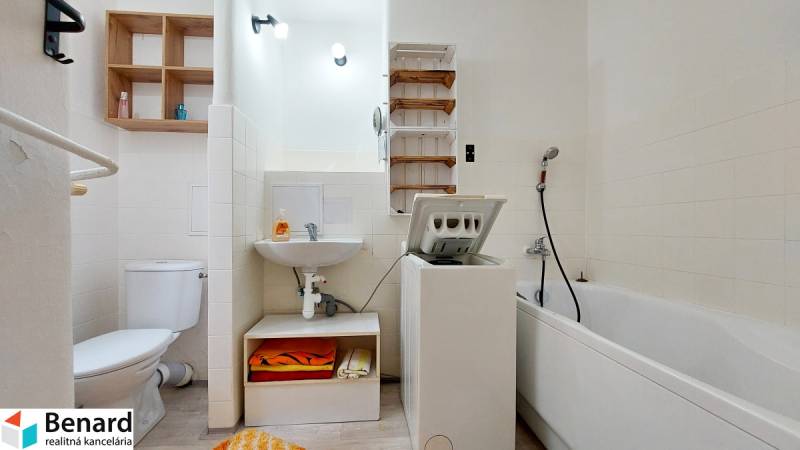 Bathroom in a 2-room apartment with a shower, washing machine, toilet, and sink.