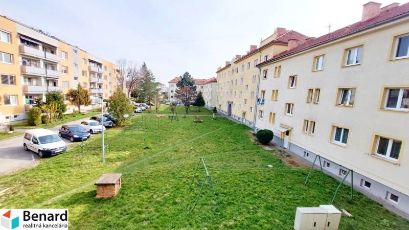 Apartment buildings and a parking lot between green courtyards on Obrancov Mieru Street in Prešov.