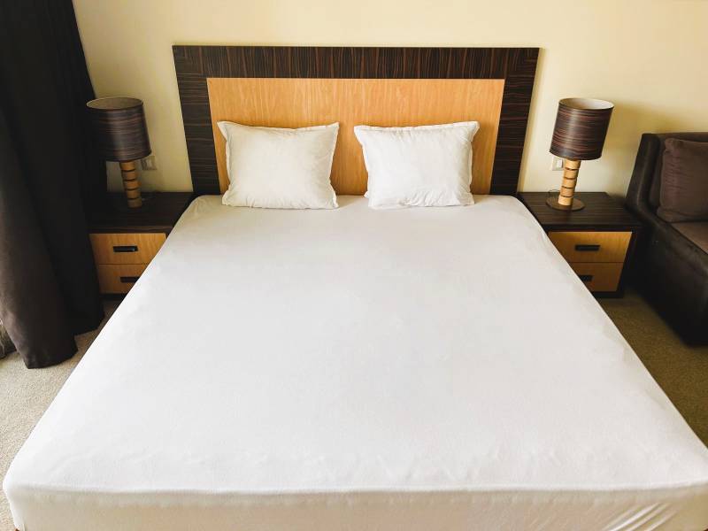 A bed with two nightstands and lamps, a studio apartment.