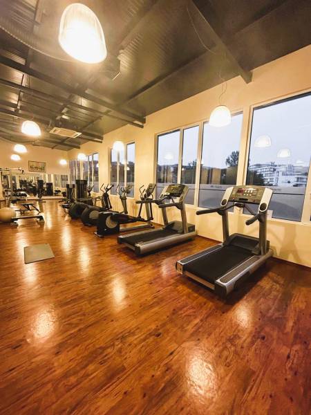 Gym with treadmills, elliptical trainers, and a floor with a wooden design.