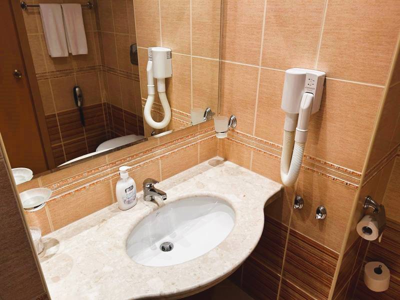 Bathroom in a studio apartment with a sink, hairdryer, marble countertop, and mirror.