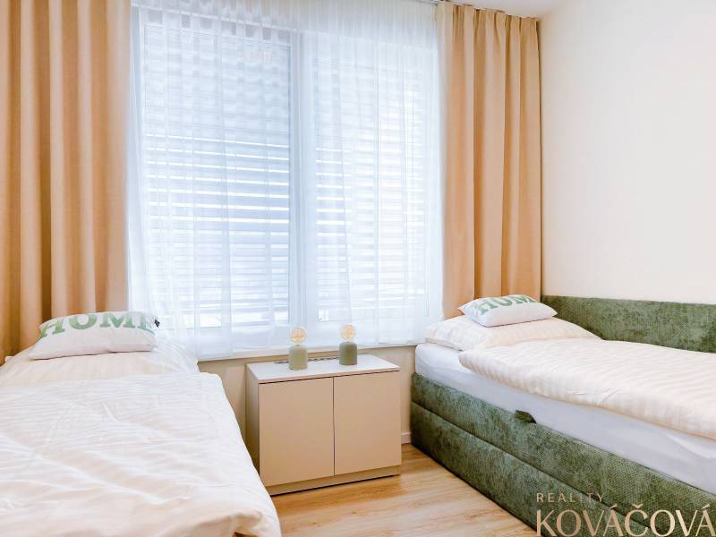 A bedroom with two beds and a wooden decor floor in a 3-room apartment.