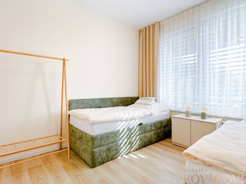 Bright room with a bed and wood-decorated flooring in a 3-room apartment.
