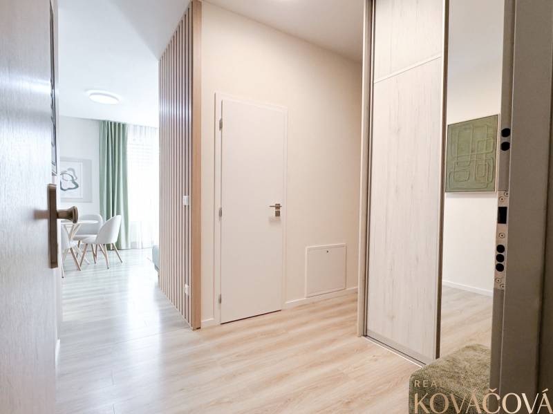 Entrance hallway with wood-patterned flooring and a dining nook in a 3-room apartment.