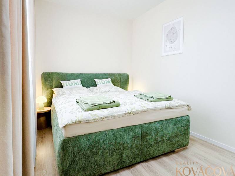 Bedroom in a 3-room apartment with a comfortable bed, wooden decor flooring, light tones.