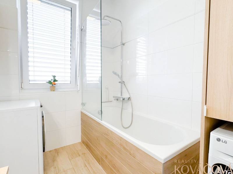 Bathroom in a 3-room apartment with a bathtub and a floor with a wooden decor.