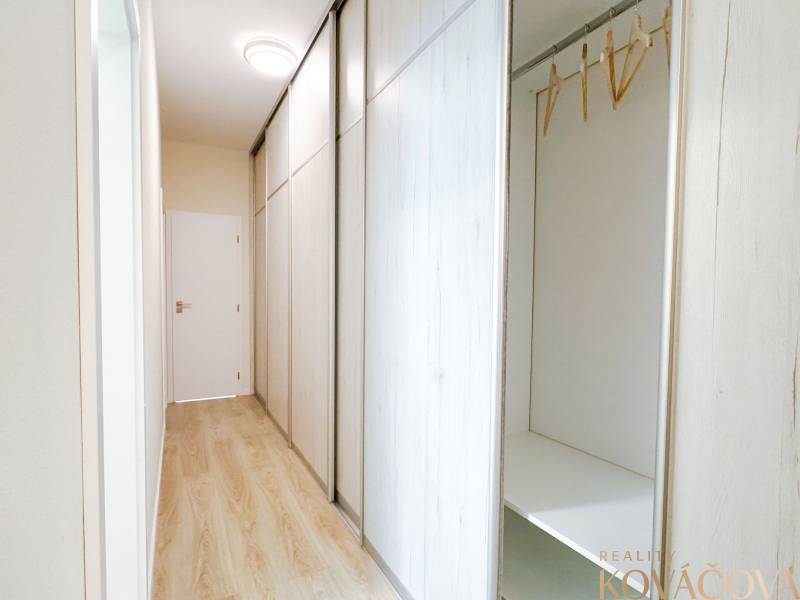 A hallway with a sliding wardrobe and a wooden decor floor in a 3-room apartment.