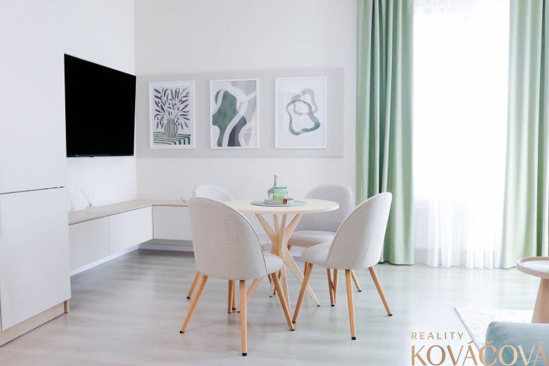 Dining area in a 3-room apartment with decorative paintings and a large window.