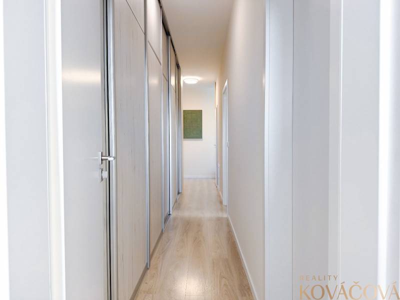 A hallway in a 3-room apartment with a wooden decor floor and built-in wardrobes.