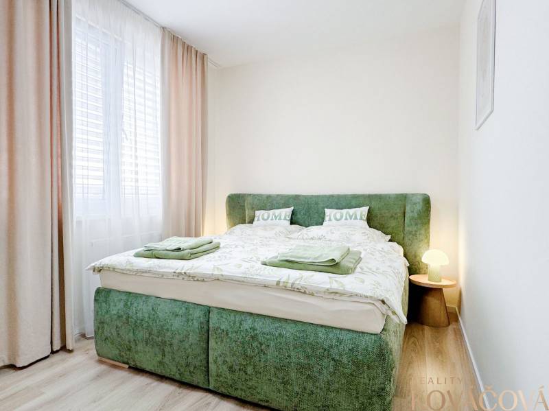 Bedroom in a 3-room apartment with a bed in green upholstery and a floor with a wooden decor.