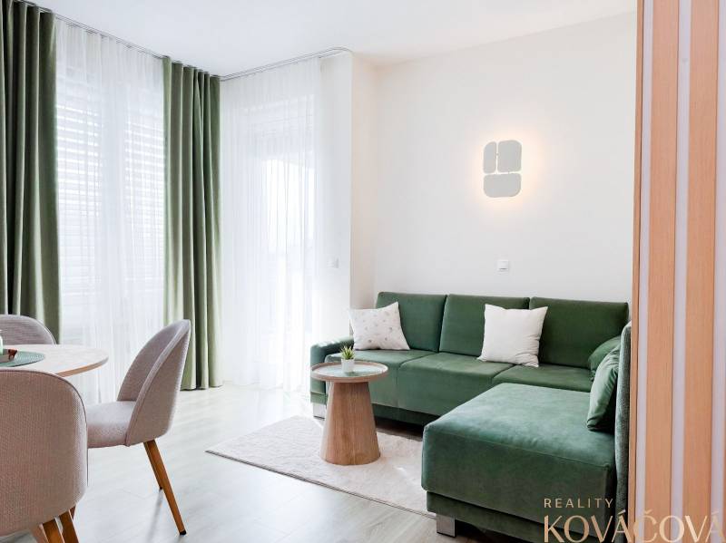 3-room apartment with a green sofa, curtains, and a floor with a wooden decor.