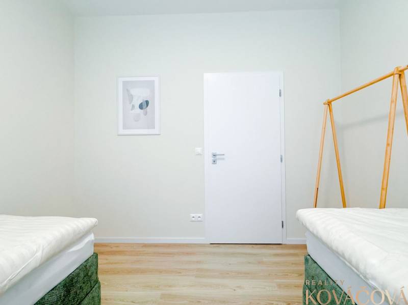 A bright bedroom in a 3-room apartment with a wood-patterned floor and minimalist decor.