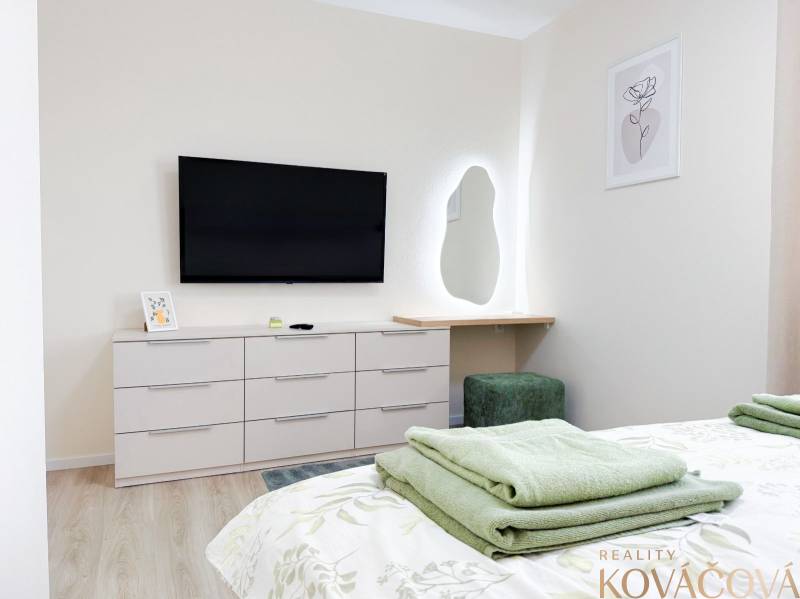 Bedroom with a TV, mirror, and dresser in a 3-room apartment, floor with a wooden decor.