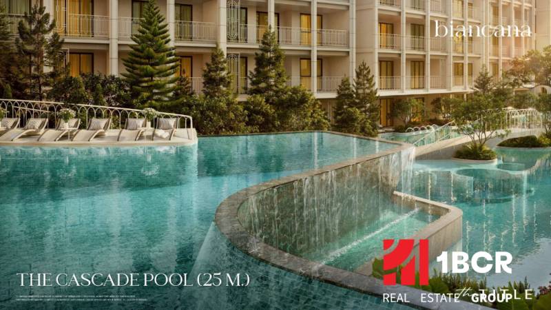 A pool with cascades during the construction of apartments in Phuket with loungers and greenery.
