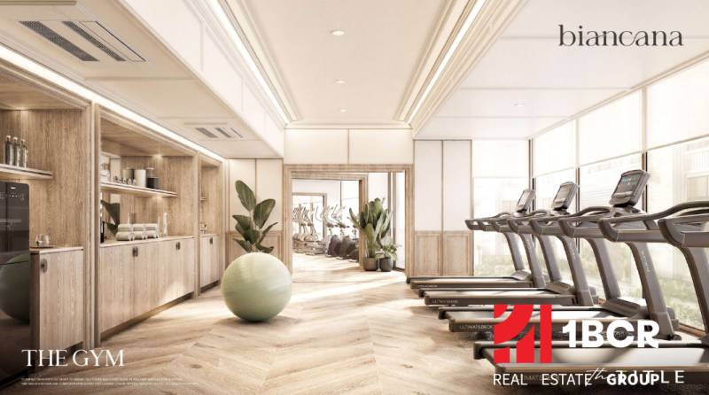 Interior of a gym with wood-patterned flooring and modern fitness equipment. Apartment construction.