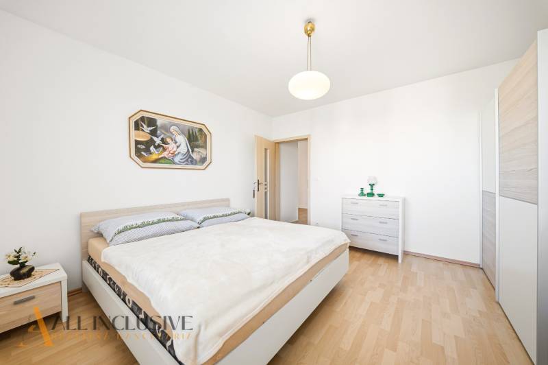 Bedroom with wood-patterned flooring in a family house and a painting on the wall.