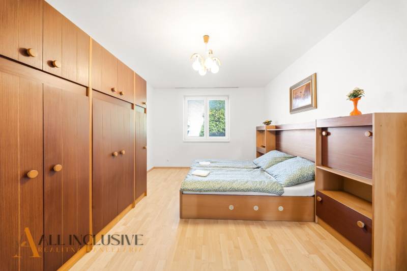 Bedroom in a family house with wood-patterned flooring, storage space, and a bed.