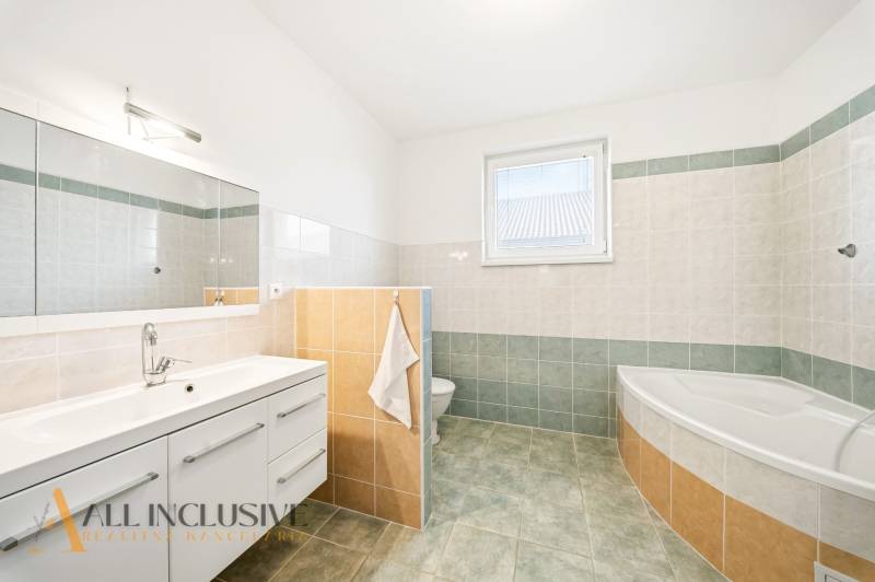 Bathroom with a bathtub, mirror, and storage space in a family house.