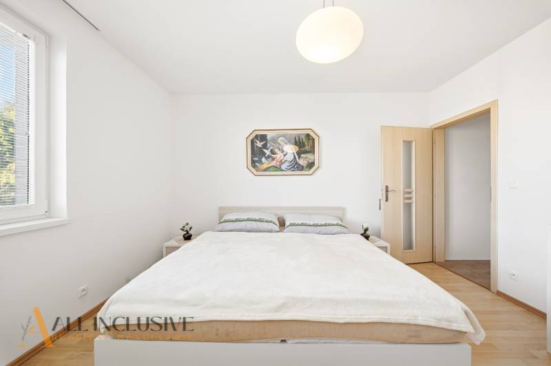 A bedroom in a family house with simple furniture and a wooden decor floor.