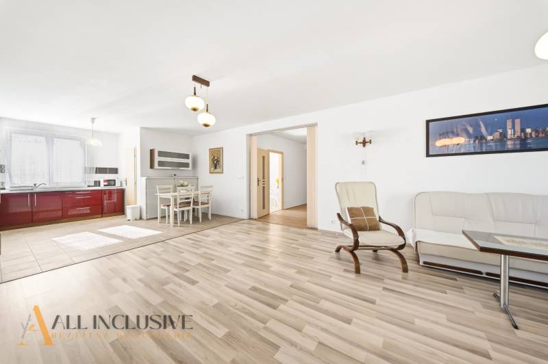 Bright living room with kitchen, wooden decor flooring, dining area.