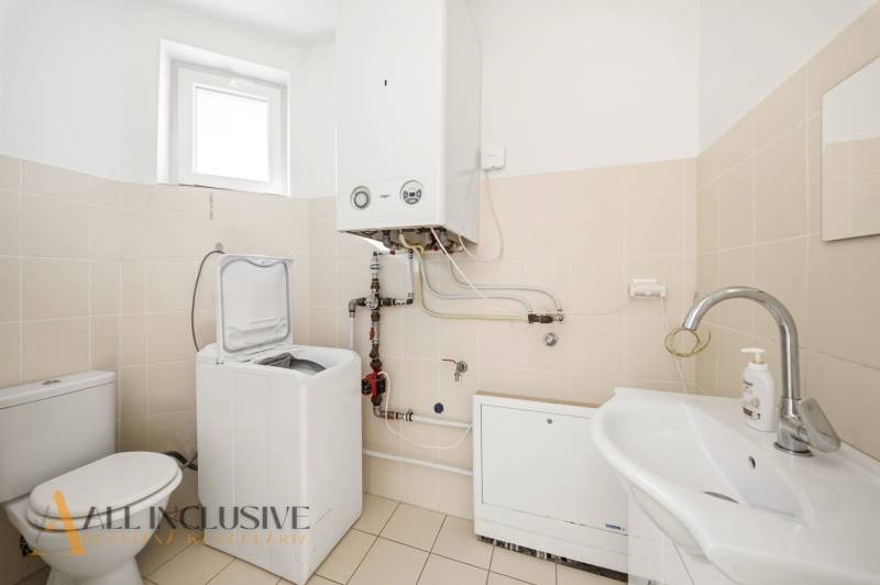 A bathroom in a family house with a tank, washing machine, and sink.