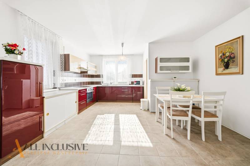 A bright kitchen in a family house with red cabinets and a dining table.