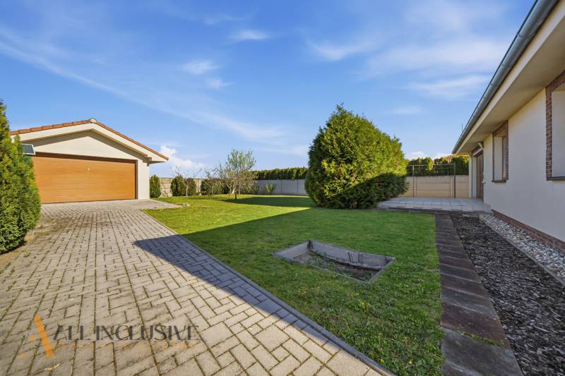 A family house in Kútniky with a garage, lawn, and paved access road.