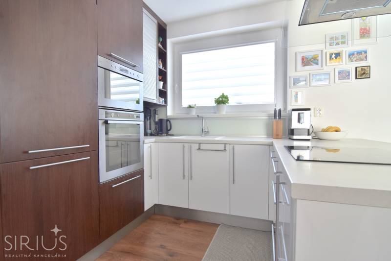 A kitchen in a 3-room apartment with a wood-patterned floor and a large window.