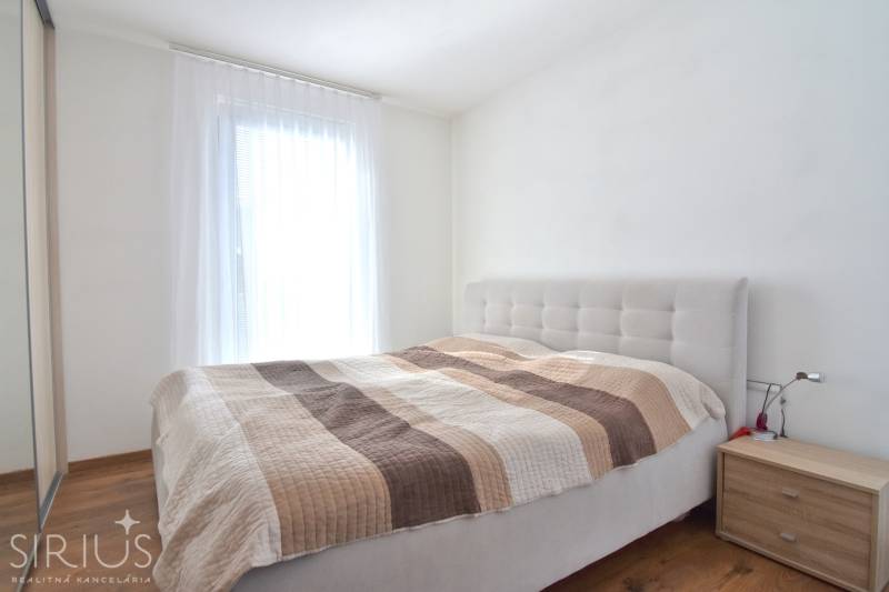 Bedroom with a bed and a nightstand in a three-room apartment, floor with wooden decor.