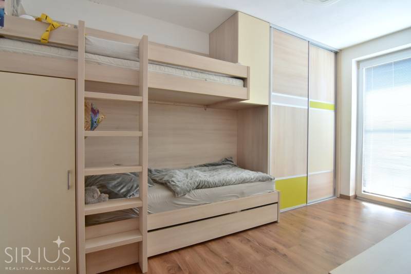 Bunk bed and built-in wardrobe in a room with a wooden decor floor.
