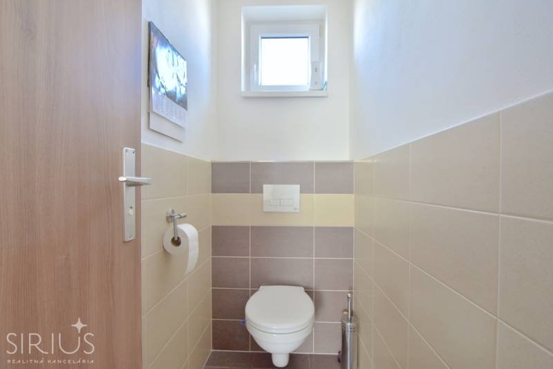 A small toilet with a window and tiles in a 3-room apartment.