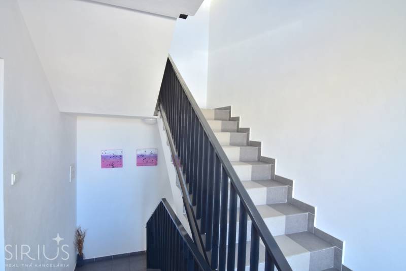 A staircase with white walls and decorations in a three-room apartment.