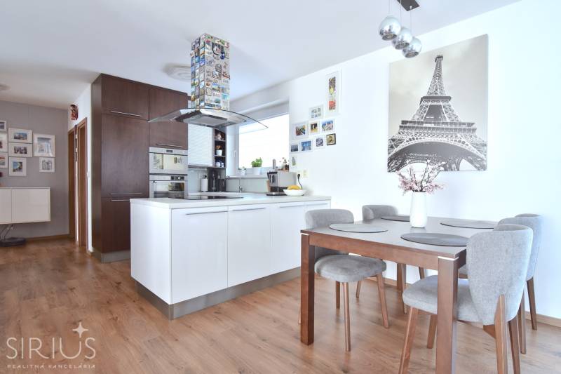 A kitchen in a 3-room apartment with a wooden decor floor and a dining table.