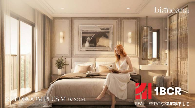 A bedroom in a 3-room apartment with a bed, a painting, and a woman reading a book.