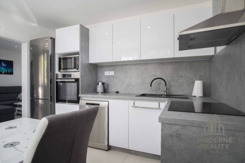 A kitchen in a 2-room apartment with stainless steel appliances and a gray countertop.