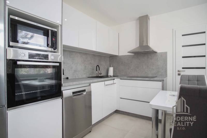 A kitchen in a 2-room apartment with built-in appliances and a dining area.