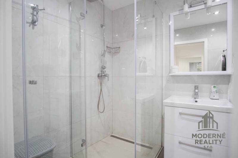 A bathroom with a shower and a sink in a 2-room apartment.