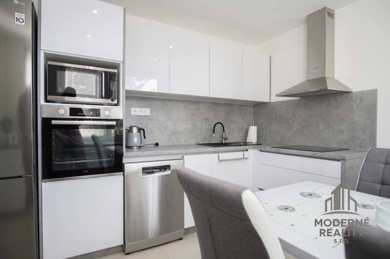 Kitchen area of a 2-room apartment with white cabinets and a gray countertop.